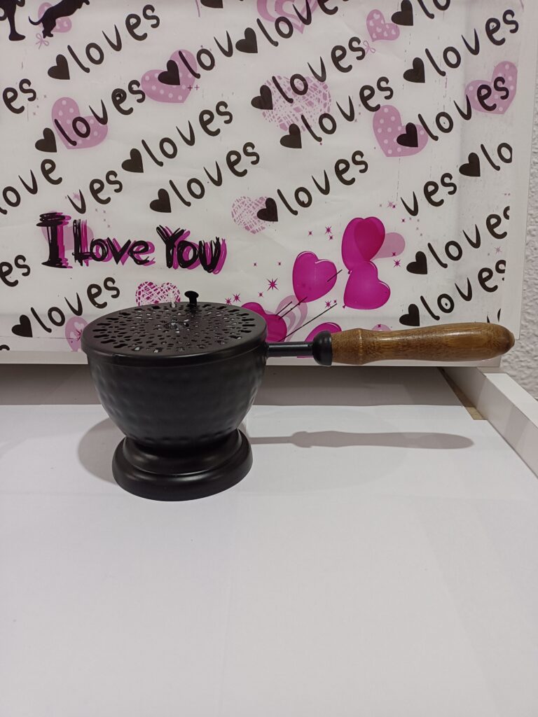 Un mortero de metal negro con una mano de madera sobre una superficie blanca con un fondo decorativo de corazones y la frase 'Te amo'